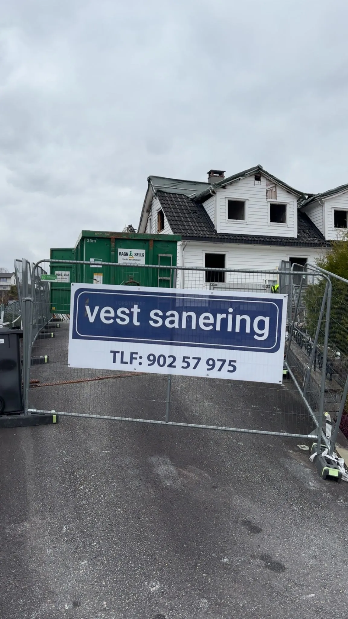 Vest Sanering-skilt på anleggsgjerde foran bygg under sanering